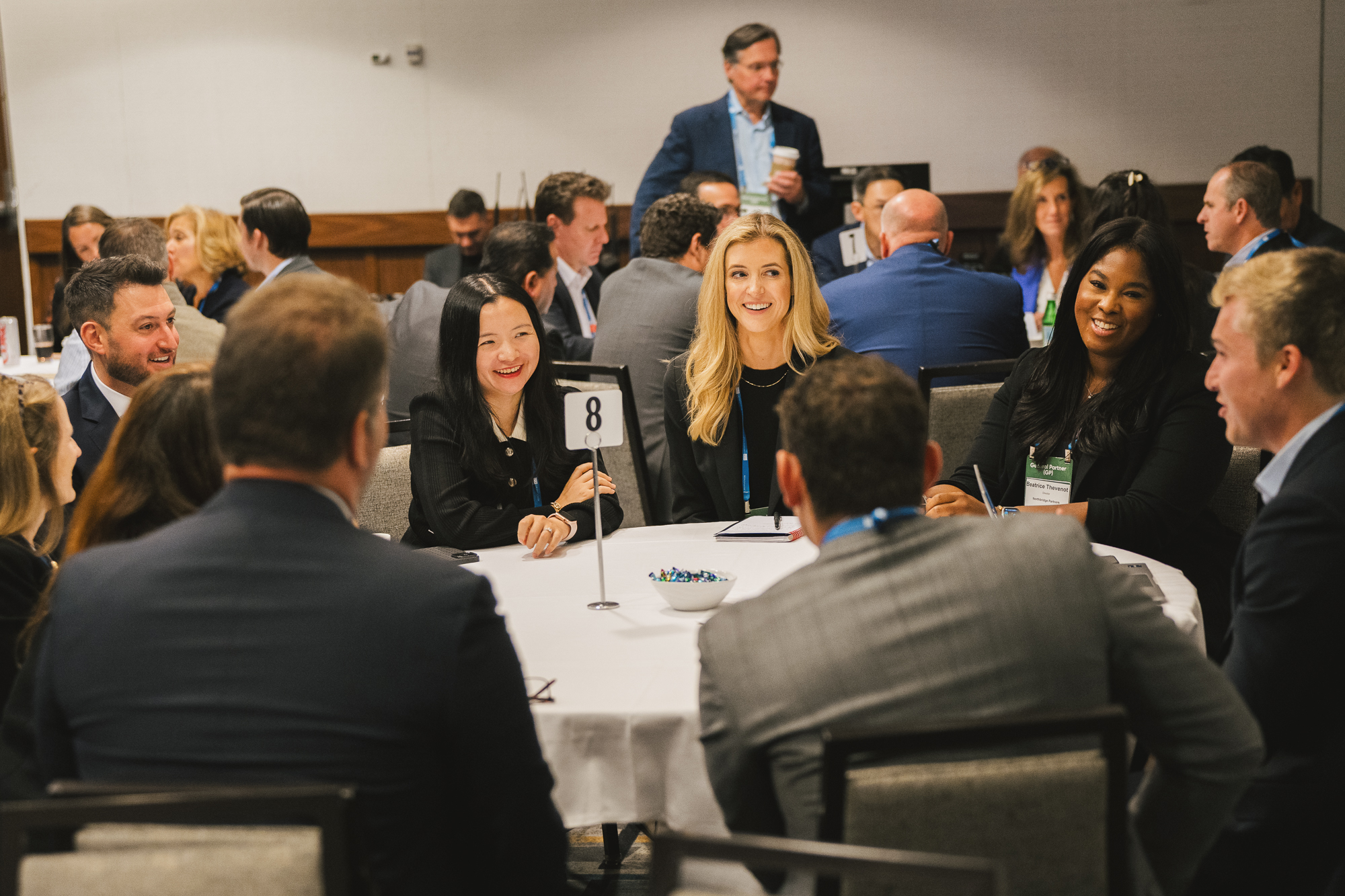 Group of people at a conference sitting around a round table talking and smiling