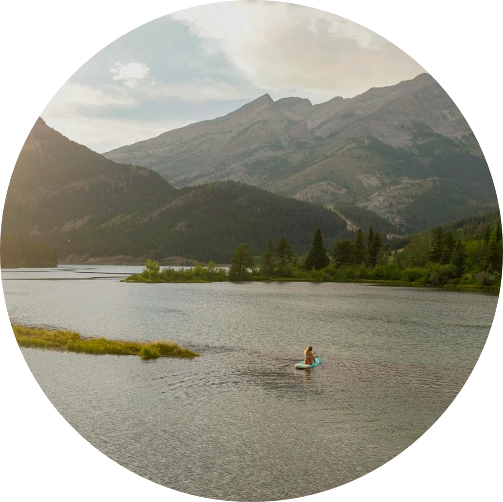 山に囲まれた川での女性のカヤックは、円の形に切り取られます